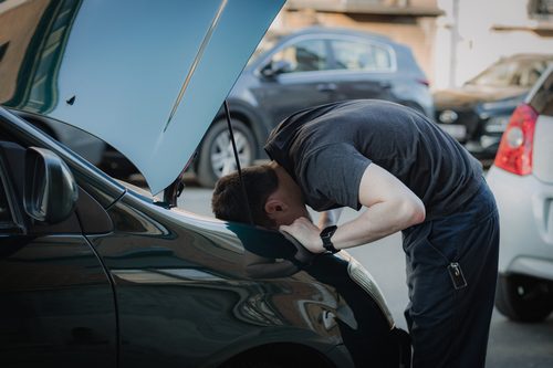 A young man takes out a car headlight bulb.