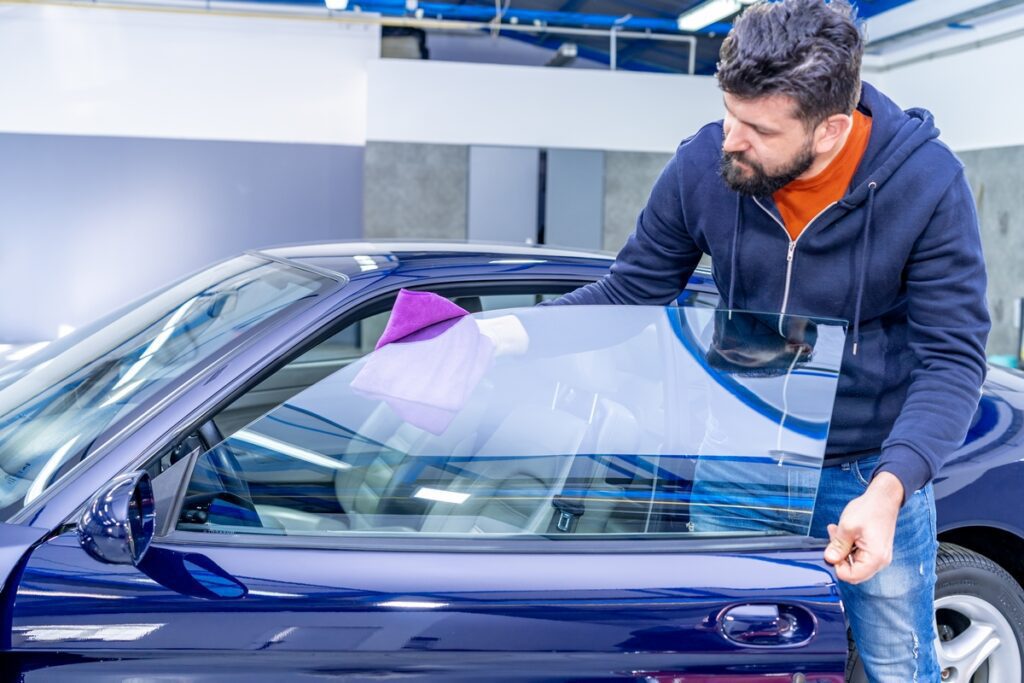 manual cleaning of luxury car windows with a microfiber towel in the garage