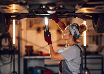 Side view of female mechanic at repair shop under chassis examin